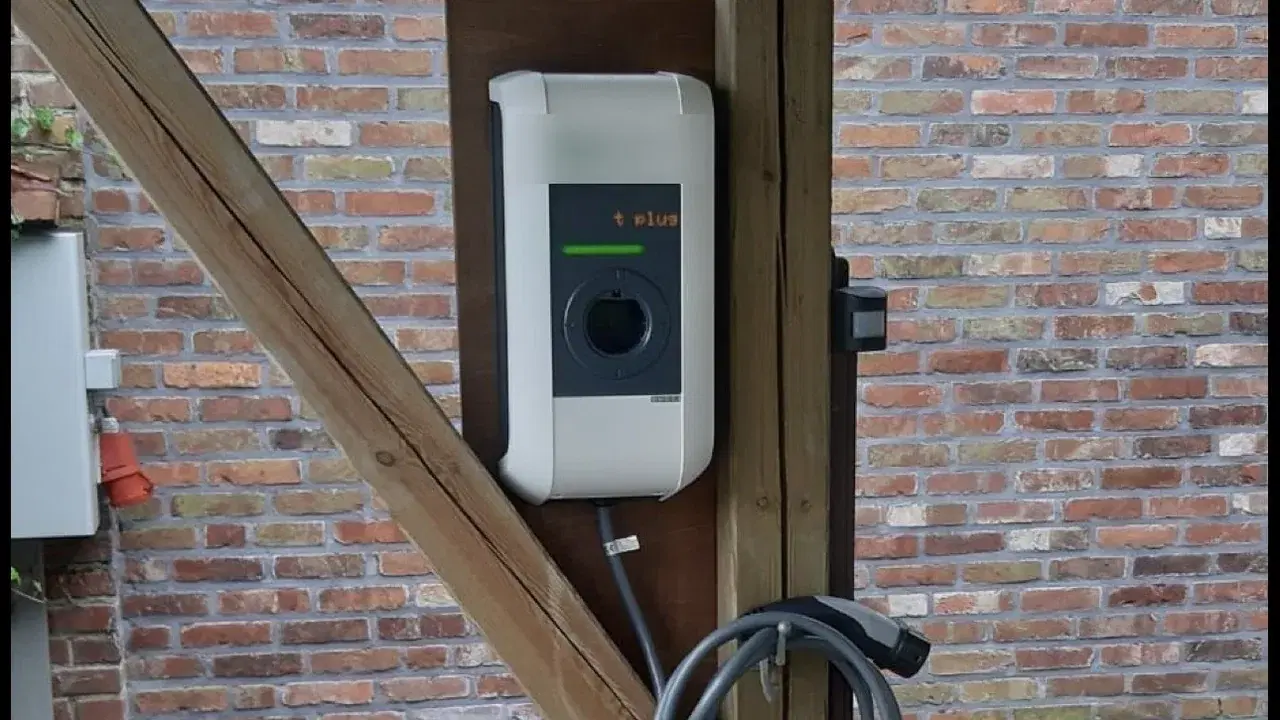 Wallbox mit Ladekabel an einem Holzpfosten unter einem Carport vor einer Klinkerwand